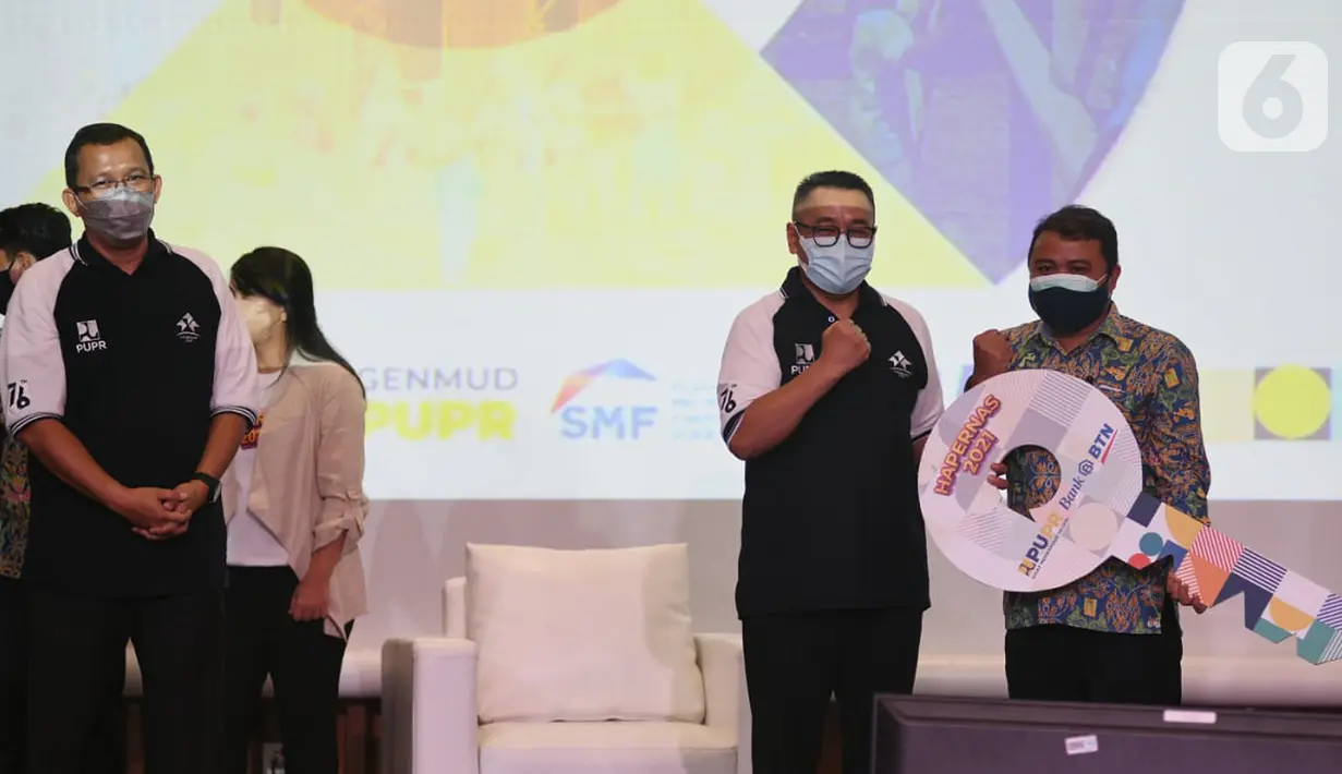 Dirjen Perumahan Kementerian PUPR Khalawi Abdul Hamid (tengah) menyerahkan secara simbolis kunci rumah kepada keluarga karyawan honorer di Jakarta, Rabu (25/8/2021). Bank BTN mendukung penyediaan dan pembiayaan perumahan untuk membantu Pemerintah mengatasi backlog perumahan. (Liputan6.com/HO/Satria)