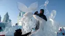 Pemahat memberikan sentuhan akhir pada patung es di festival Ice and Snow World Harbin, di Harbin, timur laut China, Jumat (3/1/2019). Menjadi acara tahunan, festival es terbesar dunia ini menghadirkan beragam patung es dengan bentuk yang besar dan mewah bagi para pengunjungnya. (NOEL CELIS/AFP)