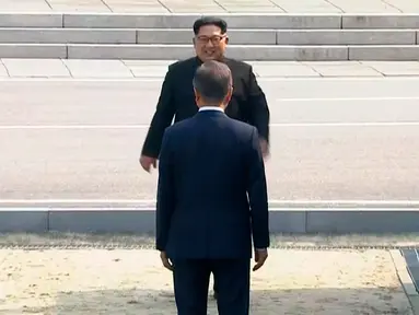Presiden Korea Selatan, Moon Jae-in menyambut kedatangan Pemimpin Korea Utara, Kim Jong-un di Zona Demiliterisasi (DMZ), Panmunjom, Jumat (27/4). Keduanya berjabat tangan sambil menempatkan senyum di bibir masing-masing. (Korea Broadcasting System via AP)