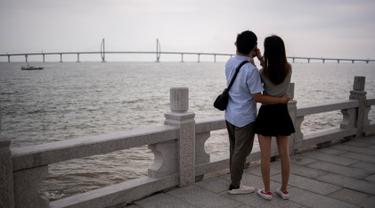 Pasangan mengabadikan Jembatan Hong Kong-Zhuhai-Makau (HKZM) di Zhuha (22/10). Jembatan laut terpanjang di dunia yang menghubungkan Hong Kong, Makau, dan daratan Cina ini akan dibuka untuk lalu lintas pada 24 Oktober 2018. (AFP Photo/Fred Dufour)