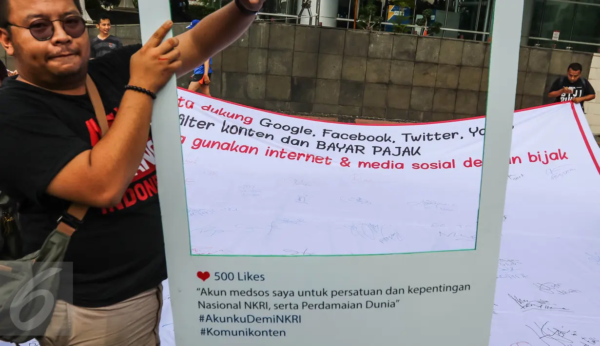 Warga memegang pigura saat aksi penandatanganan spanduk dukungan di CFD Jalan MH Thamrin, Jakarta, Minggu (25/9). Aksi tersebut juga mengajak masyarakat untuk bijak menggunakan media sosial. (Liputan6.com/Fery Pradolo)