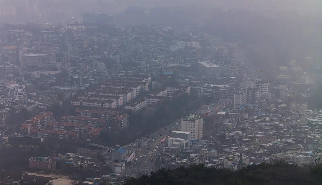 Pandangan umum menunjukkan komuter mengemudi di sepanjang jalan utama saat gedung-gedung diselimuti kabut asap pada hari yang tercemar di Seoul, Korea Selatan, Rabu (15/12/2021). (AFP/Anthony Wallace)