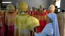 Suster Sukanya Sukchai memegang tutup kepala sutra yang akan digunakan Paus Fransiskus saat mengunjungi Thailand, Bangkok, Jumat (8/11/2019). Jubah emas-putih melambangkan kepolosan dan kegembiraan, sedangkan merah melambangkan cinta dan darah para martir. (AP Photo/Gemunu Amarasinghe)