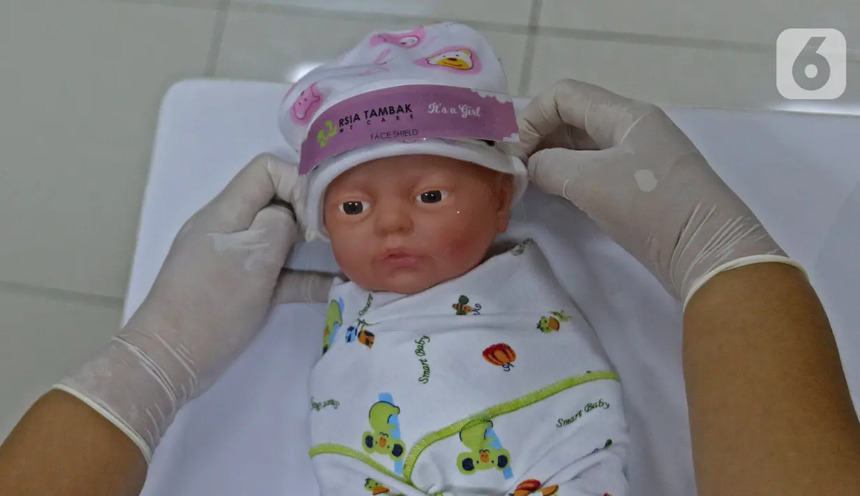 Perawat kamar bayi memasangkan face shield (italic) di  RSIA Tambak, Jakarta, Selasa (14/4/2020). RSIA Tambak membuat face shield (italic) mandiri menggunakan plastik mika, direkatkan dengan karet atau bandana menggunakan topi bayi menghindarkan alergi pada kulit bayi. (Liputan6.com/Herman Zakharia)