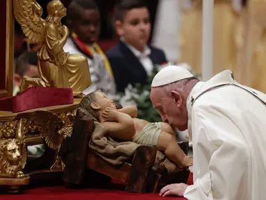 Paus Fransiskus mencium patung bayi Yesus ketika memimpin misa Malam Natal di Basilika Santo Petrus, Vatikan, Selasa (24/12/2019). Paus Fransiskus memimpin Natal bagi 1,3 miliar umat Katolik dunia. (AP Photo/Alessandra Tarantino)
