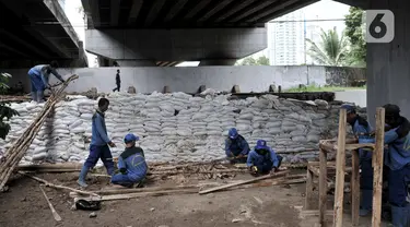 Pekerja Sudin Sumber Daya Air Jakpus menyelesaikan penutupan lubang rembesan di Tanggul Kanal Banjir Barat, Latuharhari, Minggu (5/1/2020). Penutupan untuk mengantisipasi tanggul jebol setelah diketahui terdapat rembesan di sejumlah titik akibat debit air KBB meningkat. (merdeka.com/Iqbal Nugroho)