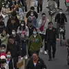 Orang-orang dan pengendara melintasi jalan pada jam sibuk malam hari di Beijing, China, Rabu (26/4/2023). (AP Photo/Andy Wong)