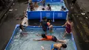 Anak-anak didampingi orang tua bermain di kolam portabel yang diberikan oleh pemerintah setempat untuk mendinginkan tubuh pada saat musim panas di Manila, Filipina (12/4). (AFP Photo/Noel Celis)