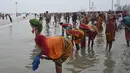 Peziarah Hindu mencuci pakaian setelah berenang selama festival Makar Sankranti di pertemuan Sungai Gangga dan Teluk Benggala di Pulau Sagar, selatan Kolkata (14/1/2022). India tengah menghadapi lonjakan kasus COVID-19 yang dipicu oleh varian Omicron yang sangat menular. (AFP/Dibyangshu Sarkar)