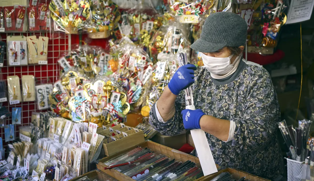 Pedagang kaki lima menjual sumpit di dekat kuil Kawasaki Daishi, di mana banyak pengunjung berdoa memohon keberuntungan selama "hatsumode", atau kunjungan pertama mereka tahun ini ke kuil atau kuil, di Kawasaki, dekat Tokyo, Senin, 2 Januari 2023. (AP Photo/Eugene Hoshiko )