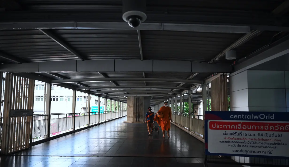Seorang biksu Buddha berjalan di sepanjang jalan kosong pada hari pertama penguncian COVID-19 yang lebih ketat di Bangkok, Senin (12/7/2021).  Thailand menerapkan lockdown untuk menekan laju penyebaran virus corona pada Senin, 12 Juli 2021 di Bangkok dan provinsi sekitarnya (Lillian SUWANRUMPHA/AFP