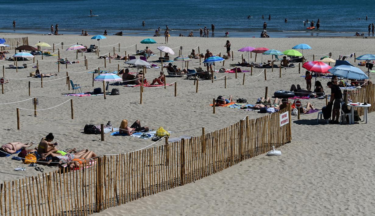 Orang-orang menikmati sore dengan area terpisah untuk mematuhi jaga jarak di pantai "Plage du Couchant" di La Grande-Motte, Prancis Selatan, Selasa (26/5/2020). Otoritas setempat membuat kotak-kotak yang dapat ditempati para pengunjung tetap bisa menjaga jarak fisik di pantai. (Pascal GUYOT/AFP)