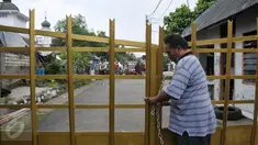 Seorang warga perumahan Eks Yon Angkub, Cililitan Besar, Jakarta, menggembok gerbang perumahan sebagai bentuk penolakan eksekusi rumah, Rabu (14/9). Eksekusi rumah di kawasan itu mendapat penolakan warga. (Liputan6.com/Yoppy Renato)