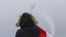 Seorang wanita menyaksikan manuver formasi udara dari tim aerobatik militer Kanada, Snowbirds, sebagai bagian dari Operation Inspiration Tour mereka selama wabah COVID-19 di atas Kota Toronto, Kanada, Minggu (10/5/2020). (Xinhua/Zou Zheng)
