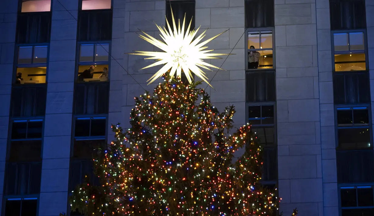 Lebih dari 50.000 lampu menghiasi Pohon Natal Rockefeller Center setinggi 75 kaki pada upacara tahunan pencahayaan di New York, Rabu (2/11/2020). Upacara yang digelar pada masa pandemi COVID-19 ini mewajibkan pengunjung untuk memakai masker, pembatasan waktu, dan jaga jarak. (AP Photo/Craig Ruttle)