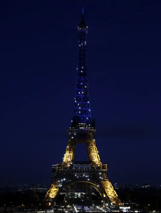 Menara Eiffel mendapat penerangan dengan warna bendera Ukraina di Paris (25/2/2022). Pasukan Rusia menyerang ibu kota Ukraina pada Jumat (25/2) dengan tembakan dan ledakan dalam invasi ke negara demokratis yang memicu kekhawatiran perang yang lebih luas di Eropa. (AP Photo/Adrienne Surprenant)