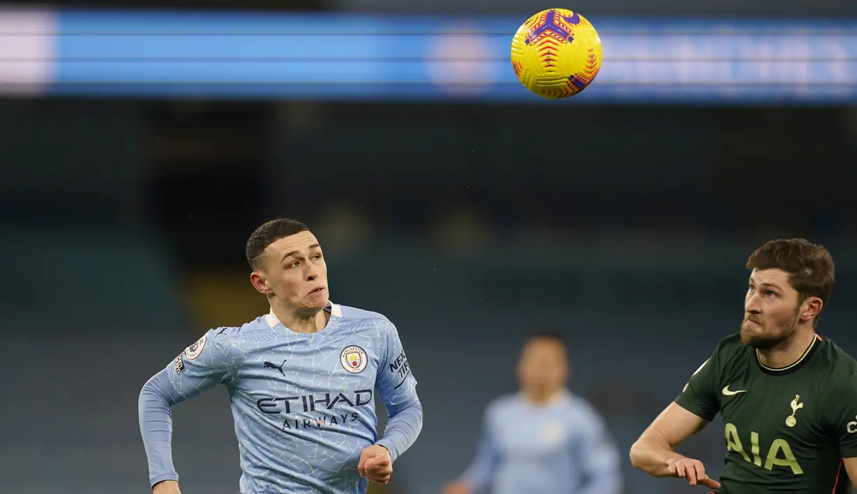 Gelandang Manchester City, Phil Foden berebut bola dengan gelandang Tottenham Hotspur, Ben Davies pada pertandingan lanjutan Liga Inggris di Stadion Etihad, Manchester, Inggris, Minggu (14/2/2021). City menang telak atas Tottenham 3-0. (Tim Keeton / Pool via AP)