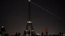 Sejumlah pengunjung berkumpul di dekat Menara Eiffel yang mengalami pemadaman sementara di Paris, Rabu (14/12). Pemadaman lampu Menara Eiffel ini sebagai simbol keprihatinan terhadap korban di Aleppo, Suriah. (AFP PHOTO/PHILIPPE LOPEZ)