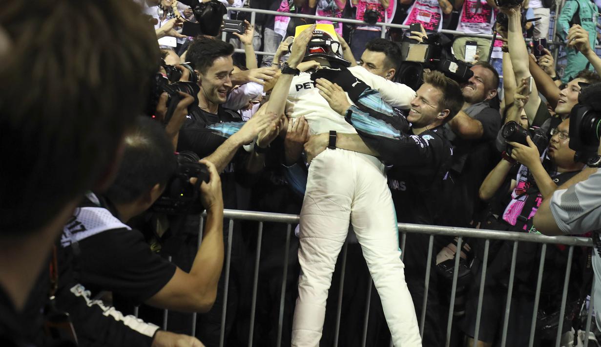 Pebalap Mercedes, Lewis Hamilton merayakan kemenangan bersama awak tim pada balapan F1 Singapura di Marina Bay City Circuit Singapore,(17/9/2017). (AP/Yong Teck Lim)