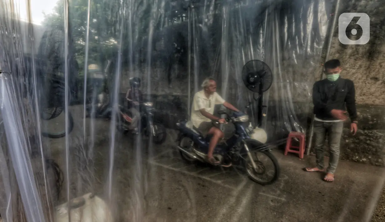 Pengendara sepeda motor disemprot cairan disinfektan saat akan memasuki pemukiman warga di kawasan H. Gari, Pesanggrahan, Jakarta, Jumat (3/4/2020). Penyemprotan secara swadaya tersebut dilakukan warga untuk mencegah penyebaran virus corona COVID-19. (Liputan6.com/Johan Tallo)