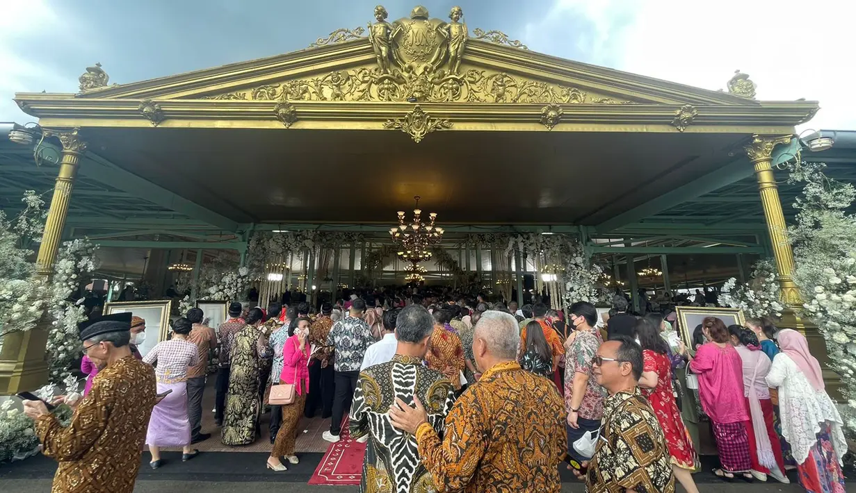 Sejumlah warga mengantre untuk bersalaman dengan putra bungsu Presiden Joko Widodo, Kaesang Pangarep dan istrinya Erina Gudono pada acara Ngunduh Mantu pernikahan di Pura Mangkunegaran, Solo, Minggu (11/12/2022). Antrean tamu undangan yang ingin berfoto dengan Kaesang Pangarep dan Erina Gudono beserta keluarga mengular panjang bahkan rela berdesak-desakan demi bisa berfoto dengan kedua mempelai. (Liputan6.com/Herman Zakharia)