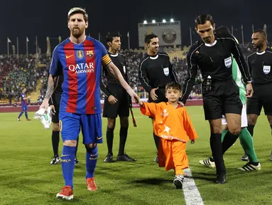 Bintang Barcelona Lionel Messi menggandeng bocah Afghanistan, Murtaza Ahmadi jelang laga melawan Al Ahli di Doha, Qatar, Selasa (13/12). Murtaza menjadi sensasi di internet karena mengenakan plastik dengan nomor punggung 10 untuk Messi. (Karim Jaafar/AFP)
