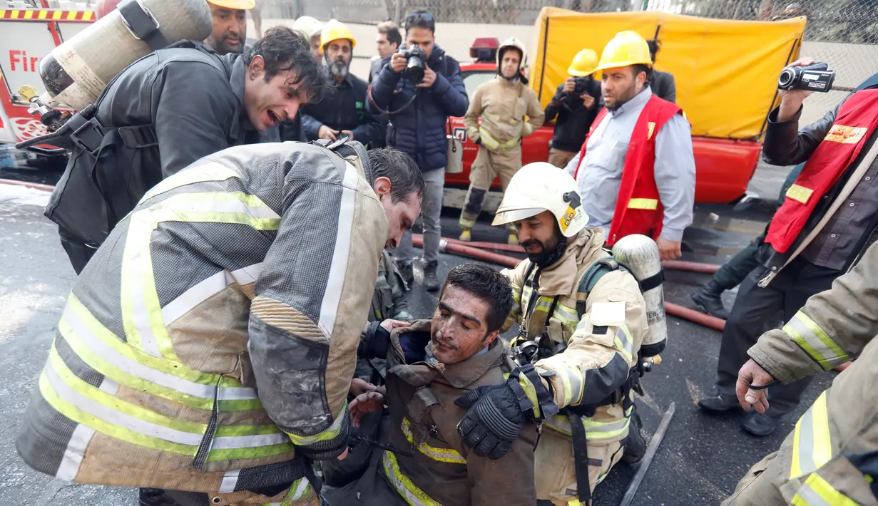 Petugas pemadam terluka saat berusaha menjinakkan api yang melahap gedung tertua Iran, gedung Plasco, di pusat kota Teheran, Kamis (19/1). Puluhan petugas damkar terjebak di dalam ketika gedung itu ambruk ke tanah dalam hitungan detik. (AFP PHOTO/STR)