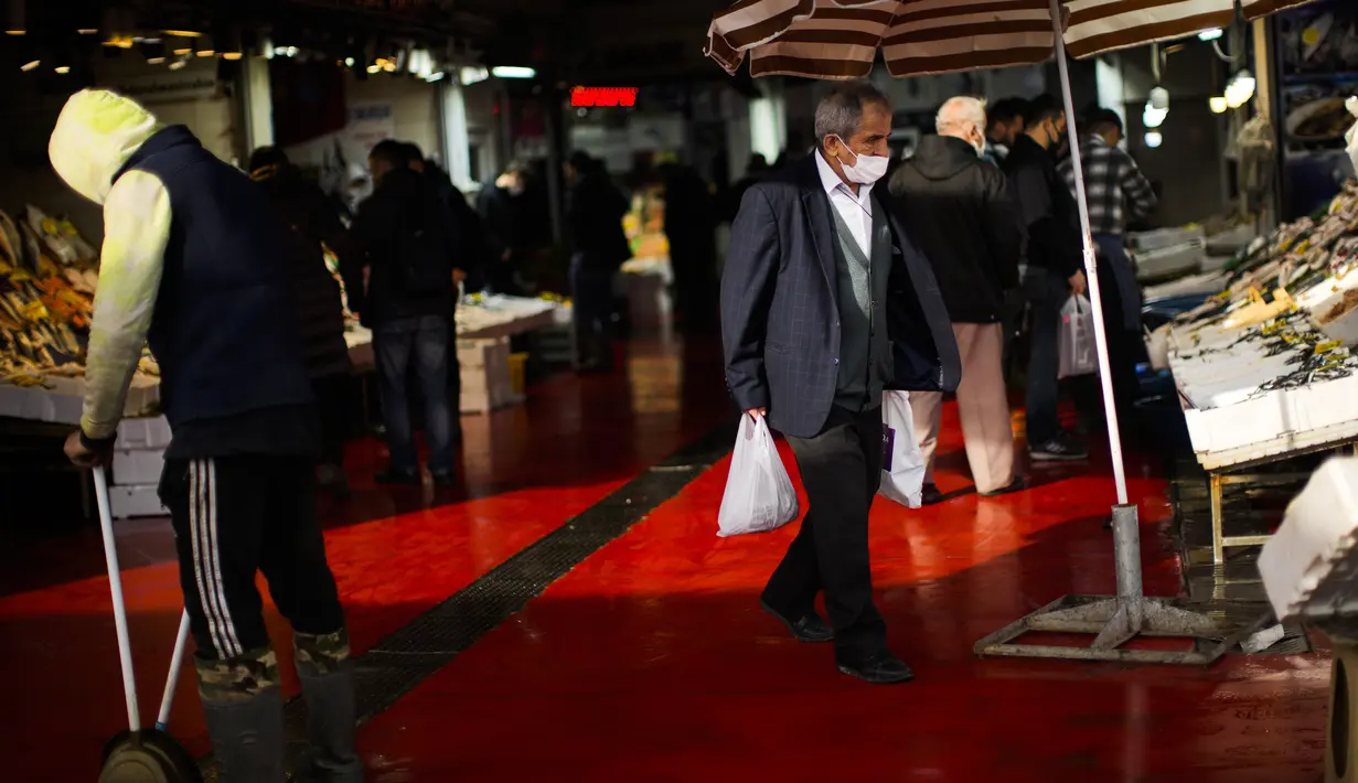Seorang pria pergi setelah membeli ikan di pasar ikan di terminal feri Karakoy, di Istanbul, Turki, Senin (3/1/2022). Inflasi tahunan Turki naik dengan laju tercepat dalam 19 tahun, melonjak menjadi 36,08% pada Desember lalu, menurut data resmi pada Senin. (AP Photo/Francisco Seco)