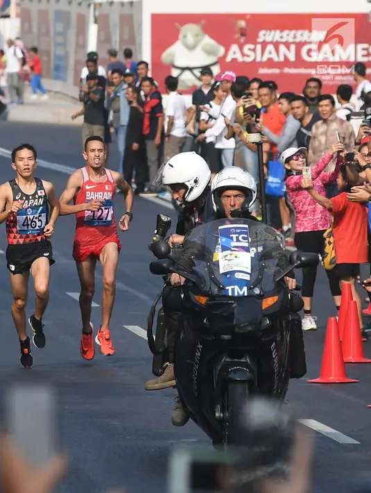 Pelari maraton Jepang, Hiroto Inoue bersaing dengan Elhassan Elabbassi dari Bahrain saat memasuki garis finis lomba Asian Games 2018 di jalan Sudirman, Jakarta, Sabtu (25/8). Hiroto menjadi pemenang lari maraton 42 kilometer. (Merdeka.com/Imam Buhori)