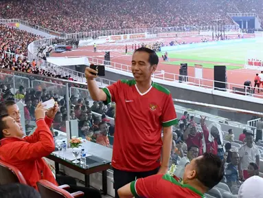 Presiden Joko Widodo (Jokowi) tampak asyik membuat vlog dengan kamera handphone saat menyaksikan laga final Piala Presiden 2018 antara Persija Jakarta vs Bali United di Stadion Utama Gelora Bung Karno, Sabtu (17/2). (Liputan6.com/Pool/Biro Pers Setpres)