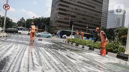 Sejumlah anggota PPSU membersihkan tumpahan oli di kawasan Jalan Thamrin, Jakarta, Selasa (4/10/2022). Akibat pembersihan ini, jalan di kawasan Sarinah dipenuhi busa. (Liputan6.com/Faizal Fanani)