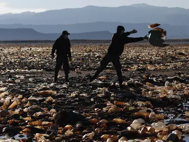 Petugas polisi membuang sampah dari Sungai Tagaret, yang mengalir ke Danau Uru Uru, dekat Oruro, Bolivia, Rabu (7/4/2021). Operasi pembersihan dimulai hari Rabu dalam upaya mengembalikan danau ke keindahan alamnya yang telah dibanjiri sampah plastik dan limbah buatan manusia lainnya. (AP/Juan Kari)