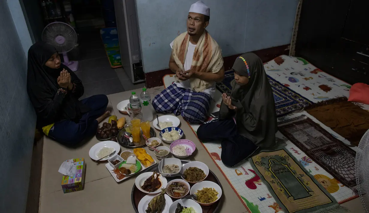 Sebuah keluarga Muslim Thailand berdoa sebelum berbuka puasa di ruang tamu rumah mereka di Bangkok, pada 28 April 2020. Banyak tempat ibadah ditutup guna membendung penyebaran Virus Corona COVID-19 ketika Umat Muslim di seluruh dunia menyambut bulan suci Ramadan. (AP Photo/Gemunu Amarasinghe)