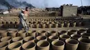 Pembuat tembikar menempatkan pot tanah liat untuk dikeringkan di sebuah bengkel di Karachi, Pakistan, Rabu (23/2/2022). (Rizwan TABASSUM/AFP)