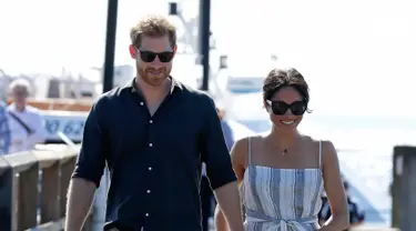 Pangeran Harry dan Meghan Markle berjalan di sepanjang Kingfisher Bay Jetty saat kunjungan ke Pulau Fraser, Australia, Senin (22/10). Meghan yang sedang hamil muda mulai menunjukkan perut buncitnya. (AP Photo/Kirsty Wigglesworth, Pool)