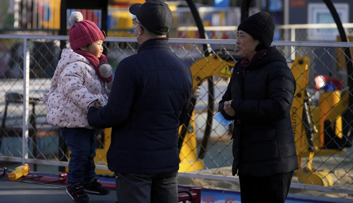 Sepasang suami istri menonton seorang anak bermain di ranjang yang memantul di sebuah taman hiburan di Beijing (17/1/2022).  Partai Komunis yang berkuasa khawatir fakta ini bisa menghalangi ambisi mereka untuk meningkatkan kekayaan nasional dan pengaruh global. (AP Photo/Andy Wong)