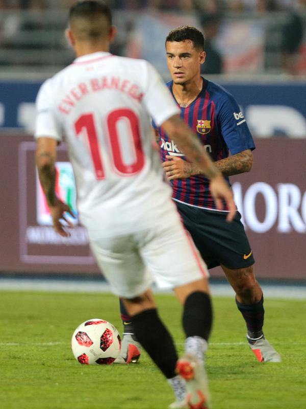 Gelandang Barcelona, Philippe Coutinho menggiring bola dari kawalan gelandang Sevilla pada pertandingan  Piala Super Spanyol di Tangier, Maroko, (13/8). Barcelona berhasil mengalahkan Sevilla dengan skor 2-1. (AP Photo/Mosa'ab Elshamy)