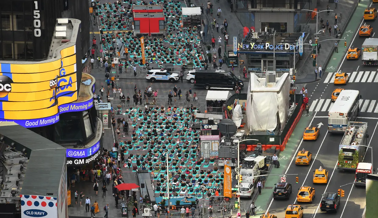 Sejumlah orang melakukan yoga bersama di kawasan Times Square, New York pada 'Summer Solstice' atau hari dengan siang terpanjang di musim panas, Rabu (21/6). Acara tersebut menandai Hari Yoga Internasional yang jatuh pada 21 Juni. (TIMOTHY A. CLARY/AFP)