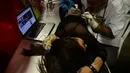 Seorang wanita terbaring saat membuat tato di tubuhnya di Expotattoo Colombia 2016 di Medellin, (16/7). Para wanita penggila tato di Kolombia tidak mensia-siakan pameran tato tersebut untuk memperbanyak tato di tubuhnya. (AFP PHOTO/RAUL Arboleda)