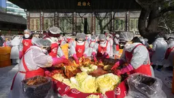 Relawan membuat kimchi untuk disumbangkan kepada tetangga yang membutuhkan, di sebuah kuil di Seoul, Korea Selatan, Kamis (2/12/2021). Sekitar 200 orang membuat 4.000 bungkus kimchi, dibuat dari fermentasi sayuran, seperti sawi putih, lobak, yang diberi bumbu pedas. (AP Photo/Ahn Young-joon)