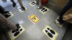 Stiker jarak sosial terlihat di lift di gedung perbelanjaan di Tokyo, Senin (28/9/2020). Ibukota Jepang mengonfirmasi lebih dari 70 kasus virus corona pada hari Senin. (AP Photo / Eugene Hoshiko)