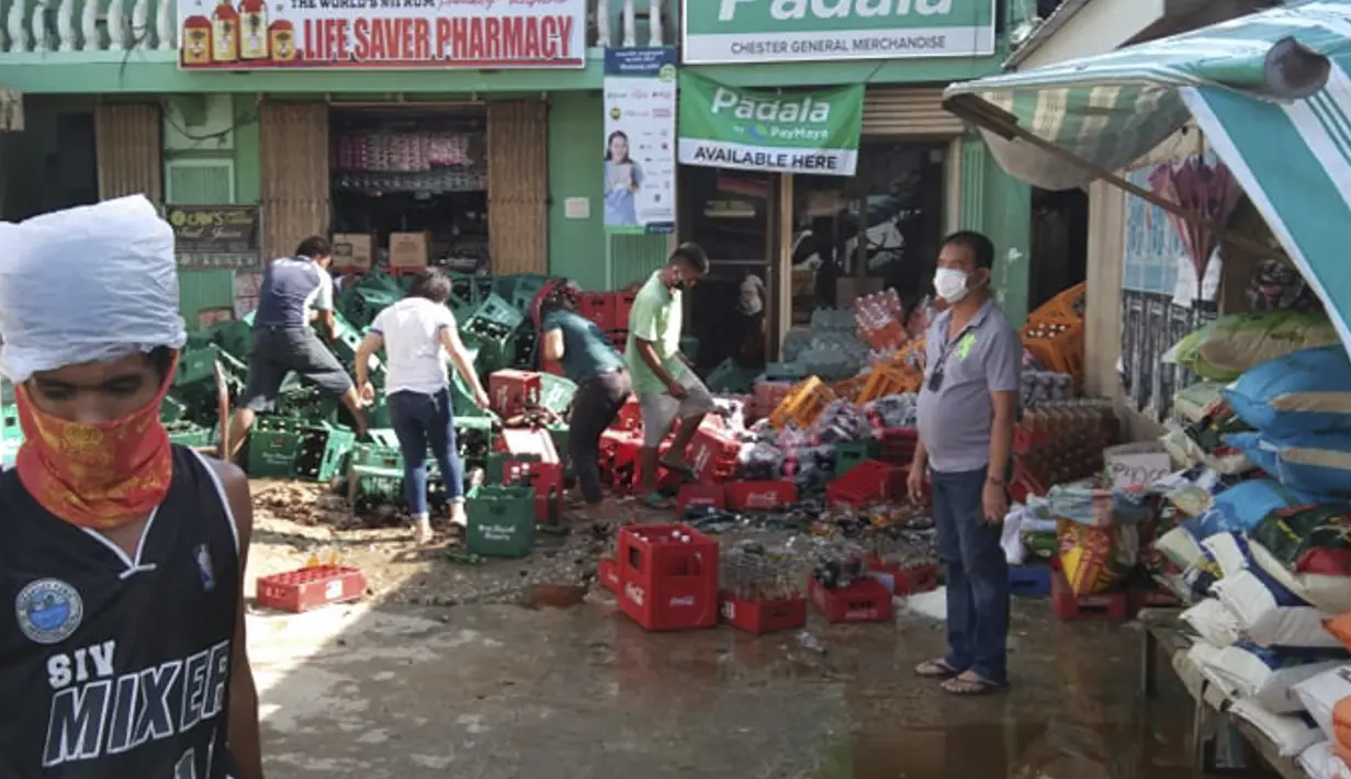 Warga menyusun botol soda yang roboh setelah gempa bumi kuat melanda Cataingan, provinsi Masbate, Filipina tengah (18/8/2020). Pusat Seismologi Mediterania Eropa (EMSC) mencatat bahwa pusat gempa berada di kedalaman 30 kilometer dari permukaan laut. (AP Photo/ Christopher Decamon)