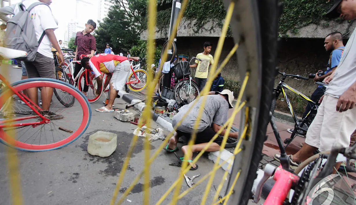 Seorang teknisi sepeda sedang memperbaiki roda sepeda salah seorang pengunjung  di kawasan Bundaran Hotel Indonesia, Jakarta, Minggu (14/12/2014). (Liputan6.com/Faizal Fanani)