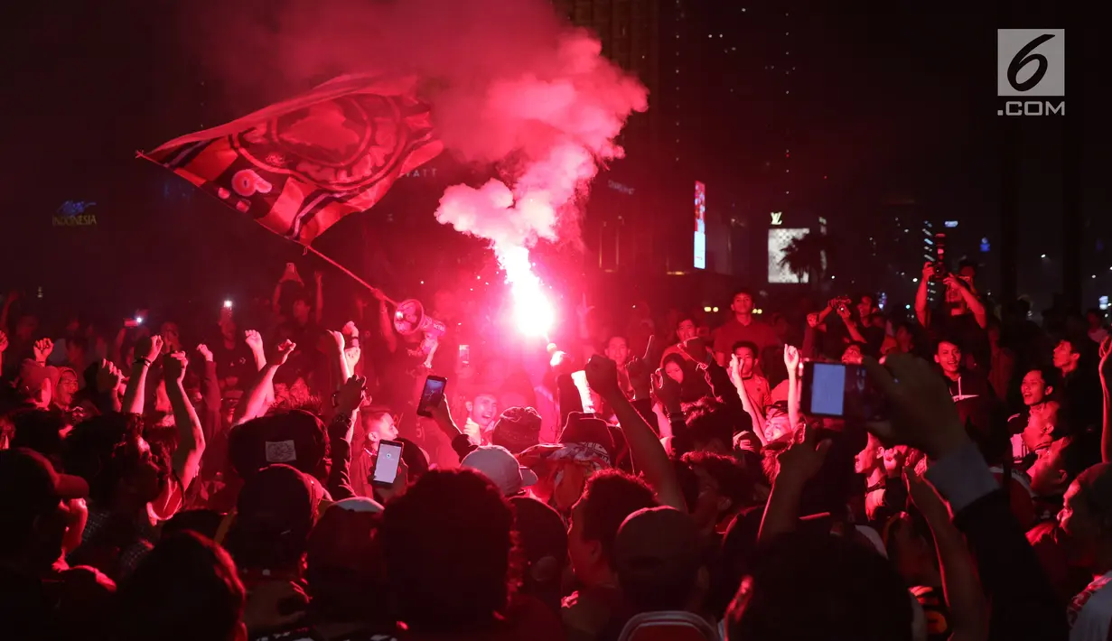 Suporter tim Macan Kemayoran menyalakan flare saat merayakan gelar juara Go-Jek Liga 1 Indonesia 2018 bersama Bukalapak yang diraih Persija di kawasan Bundaran HI, Jakarta, Minggu (9/12). Persija juara dengan 62 poin. (Liputan6.com/Helmi Fithriansyah)
