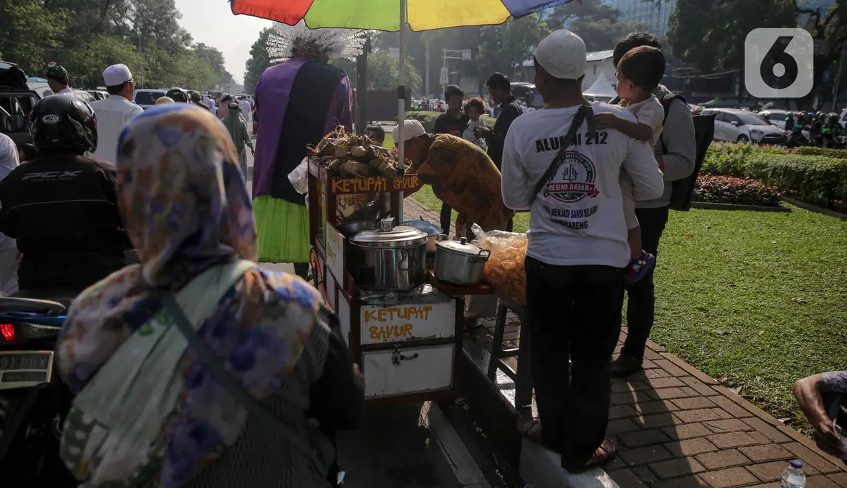 Pedagang ketupat sayur melayani pembeli saat berjualan di tengah aksi reuni 212, sekitaran Jalan Medan Merdeka Barat, Jakarta, Senin (2/12/2019). Sejumlah PKL meraup untung dengan berjualan di tengah ribuan massa Persaudaraan Alumni 212 yang mengikuti reuni di Monas. (Liputan6.com/Faizal Fanani)