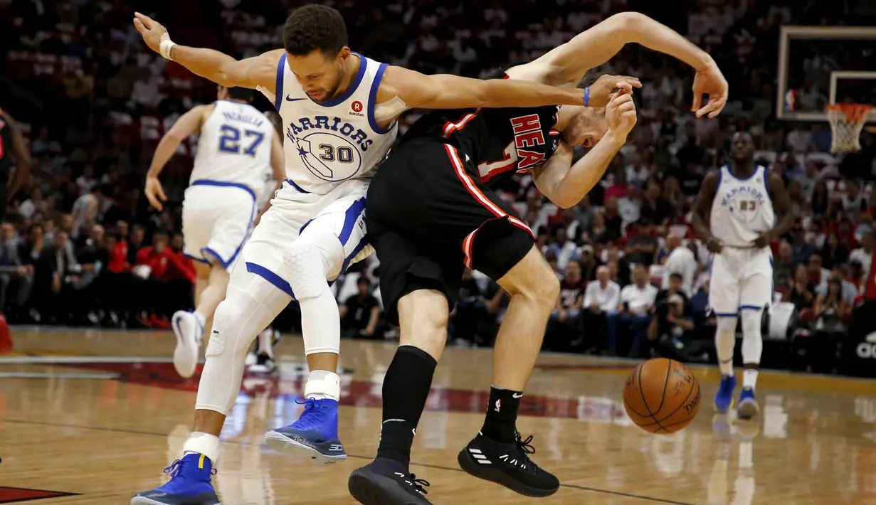 Pebasket Golden State Warriors, Stephen Curry, berebut bola dengan pebasket Miami Heat, Goran Dragic, pada laga NBA di American Airlines Arena, Miami, Senin (4/12/2017). Warriors menang 123-95 atas Heat. (AP/Joe Skipper)