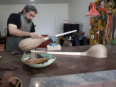 Luthier Ali Akbar Soleimani mengamplas alat musik petik bernama Tanbur yang sedang dibuat di bengkel kerjanya di Teheran, Iran pada 28 Januari 2021. Tanbur merupakan alat musik dawai berleher panjang yang berasal dari kawasan Mesopotamia, Asia Selatan atau Tengah. (AP Photo/Vahid Salemi)