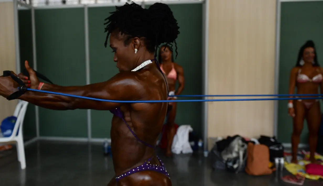 Peserta wanita melakukan persiapan sebelum tampil di kompetisi binaraga Mr. Olympia Amateur South America di Medellin, Kolombia (18/2). Sebelum berkompetisi peserta melakukan latihan fisik ringan dengan peregangan otot. (AFP Photo / Raul Arboleda) 