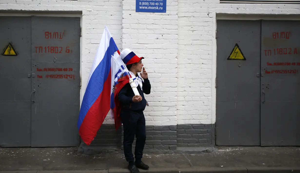 Seorang suporter Rusia menikmati suasana dekat Luzhniki stadium di Moskow, Rusia, (14/6/2018). Rusia akan melawan Arab Saudi pada laga pembuka. (AP/Rebecca Blackwell)