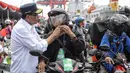 Menhub Budi Karya Sumadi memasangkan helm peserta mudik gratis sepeda motor saat menyambut kedatangan mereka di Pelabuhan Tanjung Priok, Rabu (20/6). Ada 699 sepeda motor dan 1.650 penumpang kembali ke Jakarta dari Semarang. (Liputan6.com/Faizal Fanani)